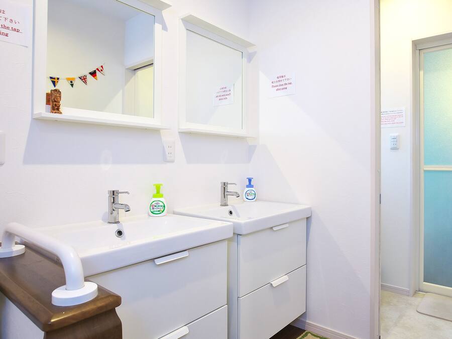 Une salle de bain avec deux lavabos, un miroir et une porte dont les panneaux sont en verre dépoli.