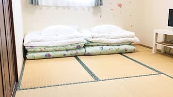 Una habitación con una cama, un televisor sobre un mueble bajo y una pared decorada con diseños florales.