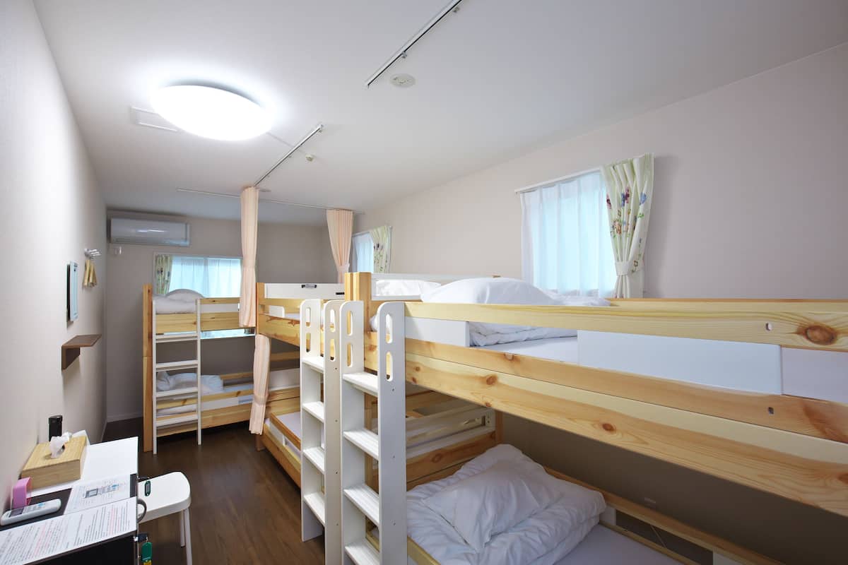 A bunk bed room with a desk, a chair, and a window with curtains.