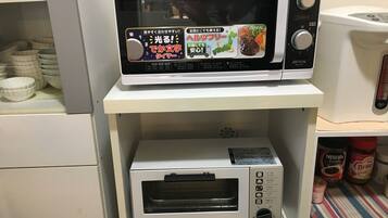 Eine Küche mit einer Mikrowelle auf einem Regal und einem Toaster darunter.