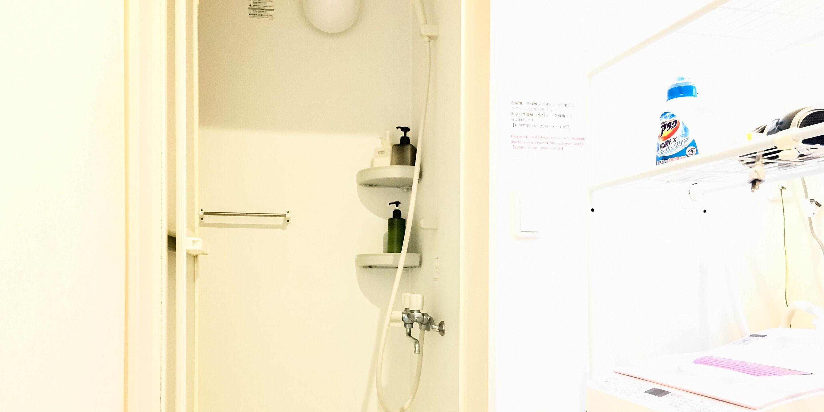 A bathroom with a shower, a towel rack, a soap dispenser, and a water bottle on the wall.