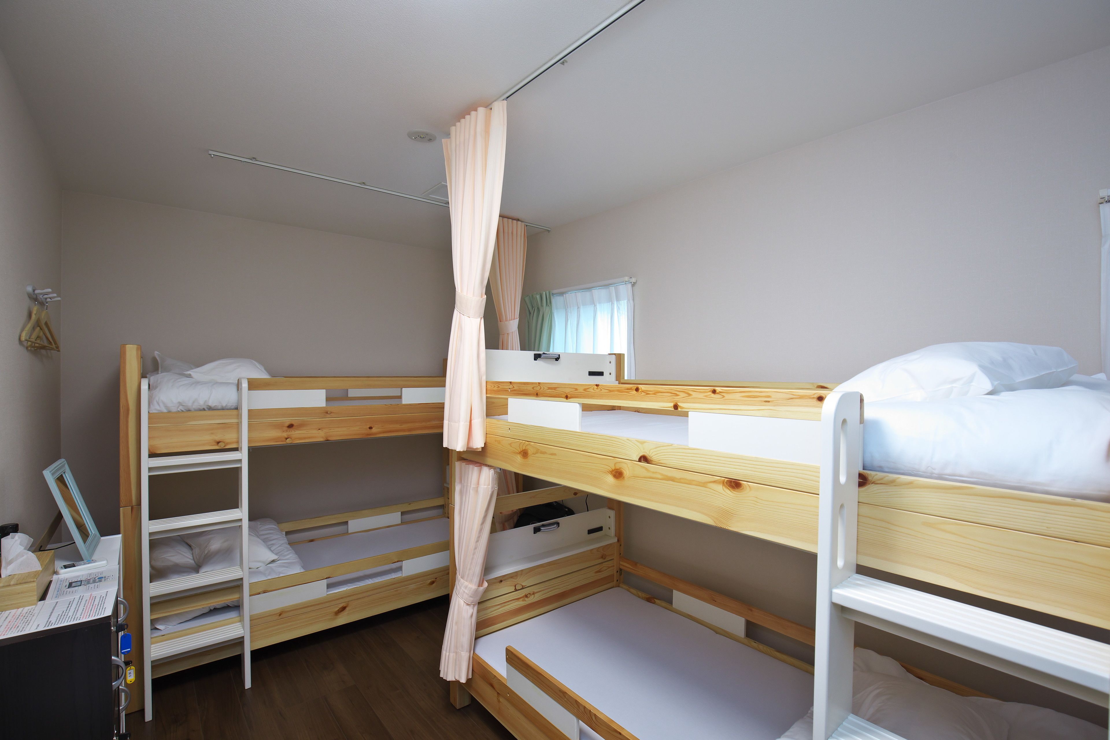 Une chambre avec un lit superposé, un rideau, un bureau avec une chaise et une fenêtre également dotée de rideaux.