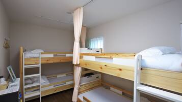 Une chambre avec un lit superposé, un rideau, un bureau avec une chaise et une fenêtre également dotée de rideaux.