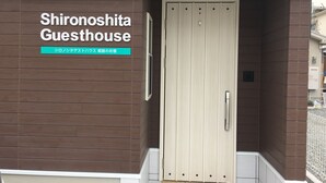 Una entrada de edificio moderno con un letrero que dice "Shironoshita Guesthouse" y texto japonés debajo.