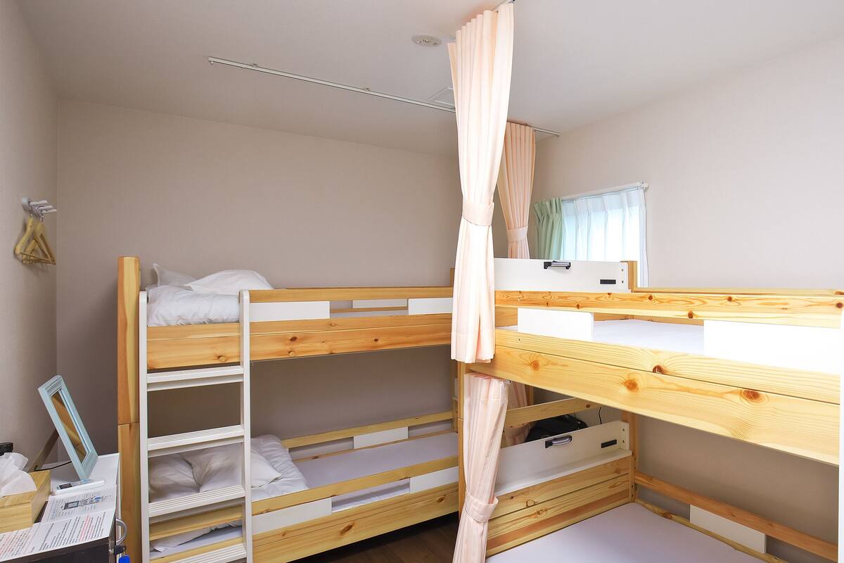 A bunk bed room with a desk and a mirror.