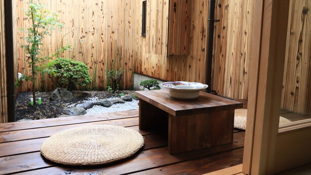 A wooden deck with a small table and a woven mat. - Murasakino Uan (Kyoto)
