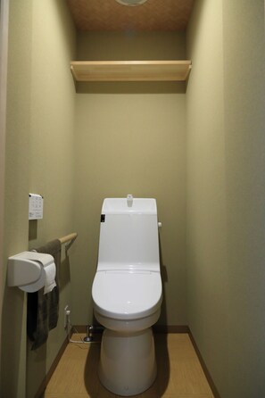 Ein kleines, sauberes Badezimmer mit Toilette, Waschbecken und Handtuchhalter.
