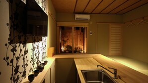A modern kitchen with a wooden countertop, a stainless steel sink, and a decorative wall with a floral pattern. - Murasakino Uan (Kyoto)