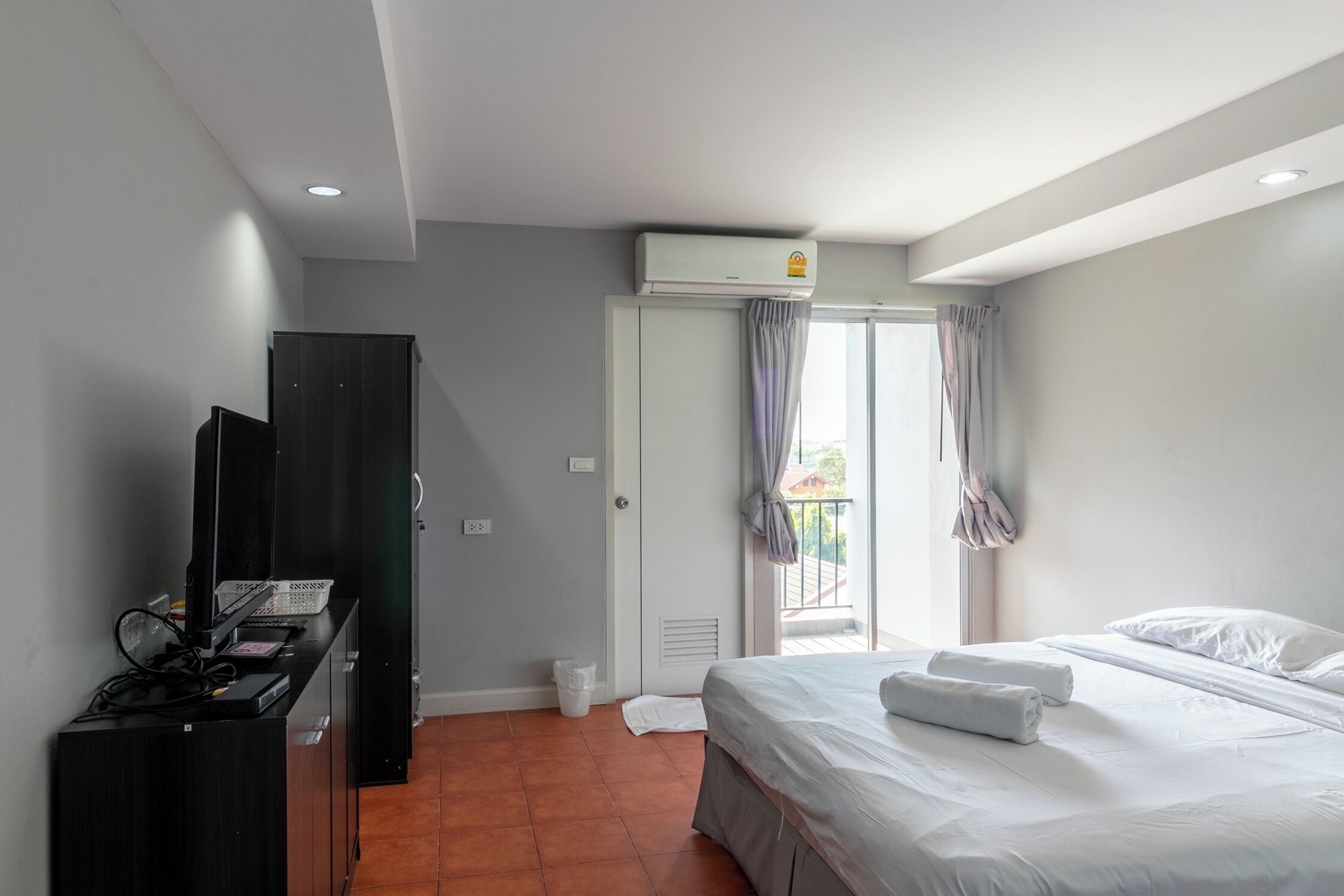 Hotelkamer met een bed, televisie, kledingkast, airconditioning en een raam met gordijnen.