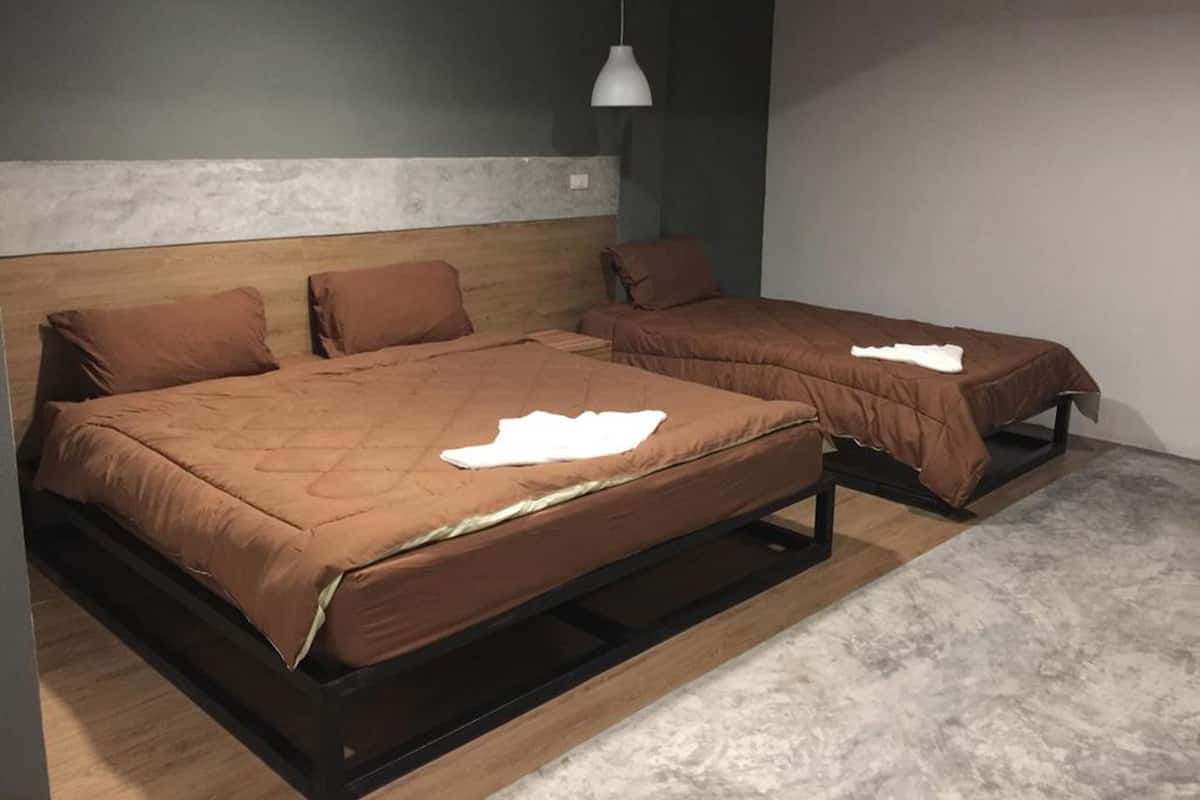 Een moderne slaapkamer met twee bedden, een houten hoofdbord en een grijze accentmuur.