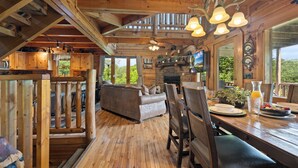 A wooden interior with a dining area, sofa, and fireplace.