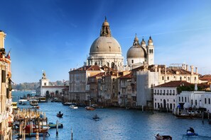 Un canale storico veneziano con gondole, un edificio a cupola ben visibile e architettura tradizionale.