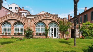 A brick building with arched windows and a well-maintained lawn.