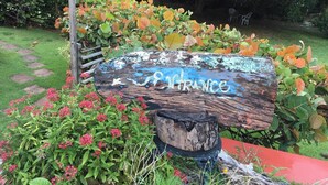 Un senyal de fusta rústic amb la paraula 'FRANCE' pintada, envoltat de verdura abundant i plantes en flor.