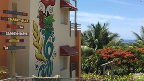 Edifici amb un mural colorit i indicadors direccionals per a botiga de records, Villa Shack, platja, taller al jardí, despatx i estudi de Jobos.