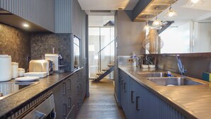 Een moderne keuken met een roestvrijstalen spoelbak, een broodrooster en een koffiezetapparaat. Er is een trap die naar een ander niveau leidt.