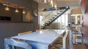 Een moderne keuken met een groot keukenblok, hanglampen en een trap naar een hoger niveau.