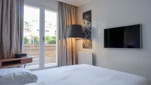 Hotelkamer met een bed, een aan de muur bevestigde televisie, een lamp en uitzicht door het raam.