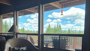 Une pièce dotée d’une grande fenêtre, d’un canapé en cuir, d’une table et offrant une vue sur les arbres et les montagnes.
