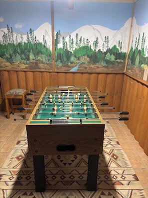 A foosball table in a room with wooden walls and a mural of a forest and mountains. - Specializing in Micro Weddings and Corporate Retreats. Large meeting event space (Breckenridge)