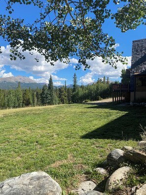 A grassy field with a wooden deck and a mountain in the background.