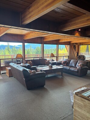 Un salon chaleureux avec un grand canapé, une table basse et une vue sur les montagnes.