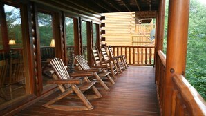 A wooden deck with rocking chairs and a wooden railing.