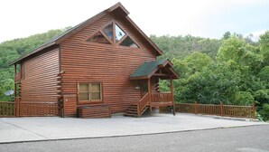 A log cabin with a balcony, a porch, and a small window.