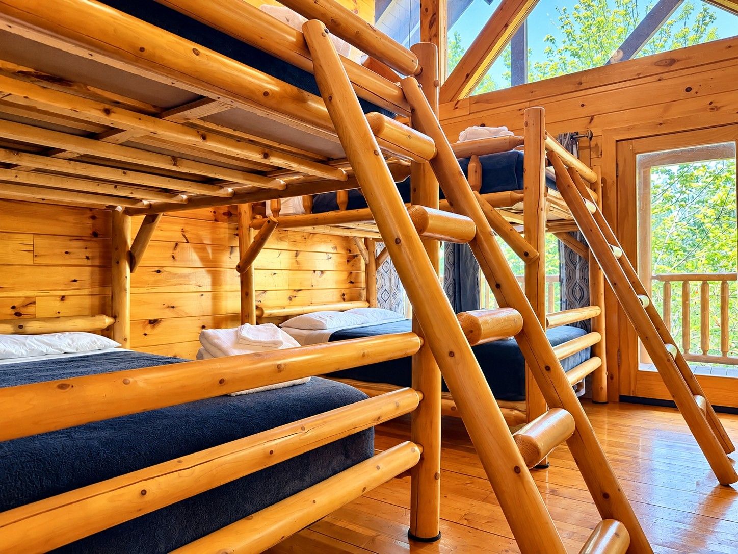 A wooden cabin interior with bunk beds and a wooden ladder.