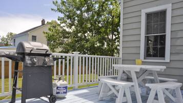 A deck with a barbecue grill, a propane tank, and picnic tables.