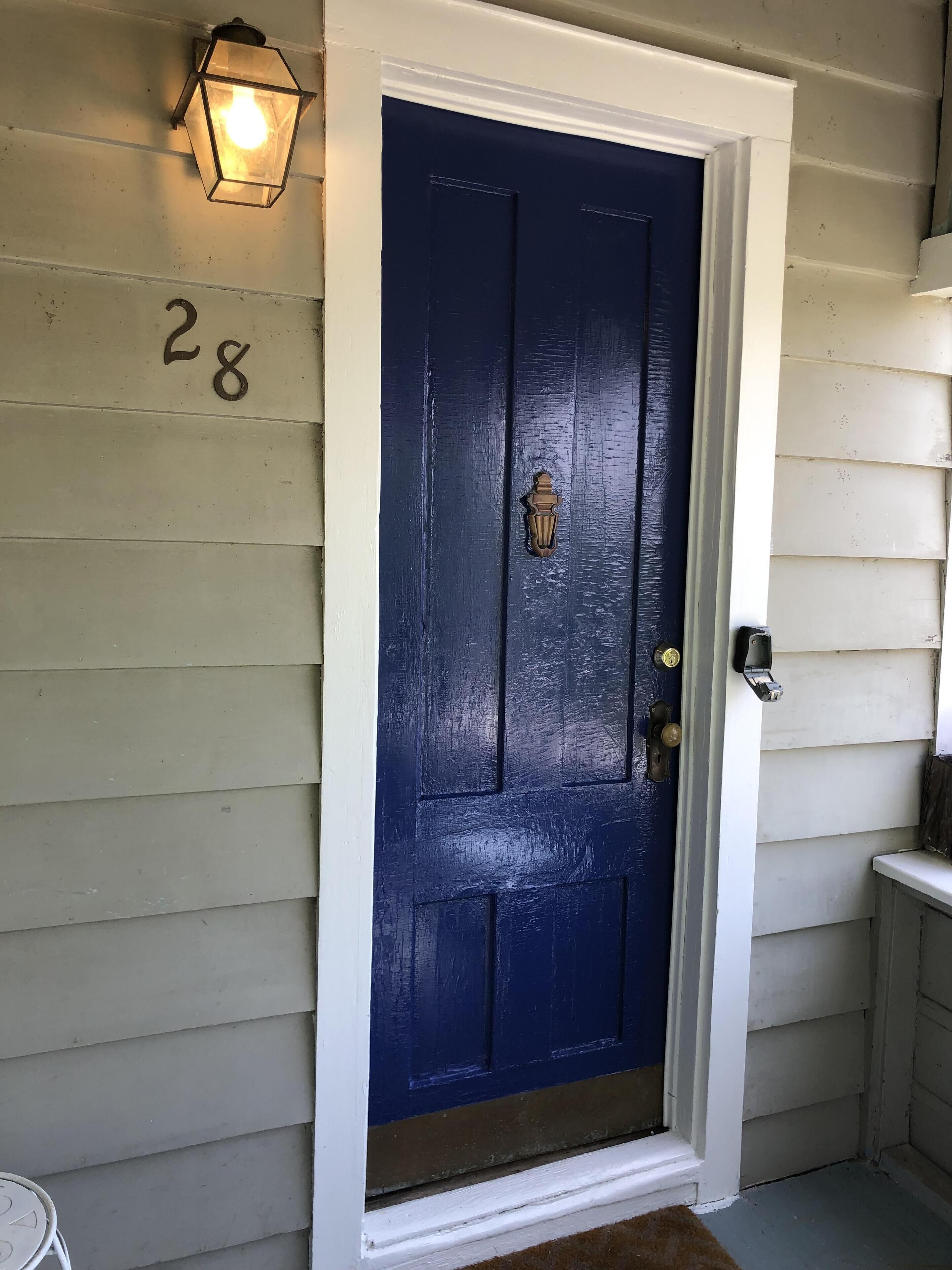 A dark blue door with a brass knocker and a light fixture above it.