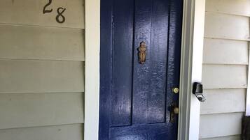 A dark blue door with a brass knocker and a light fixture above it.