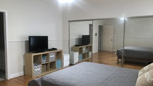 A bedroom with a bed, a TV on a wooden stand, a wardrobe, and a mirror. - Energy Corridor - long term rental. Utilities included!! (Houston)