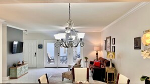 A spacious living room with a chandelier, a dining area with a table and chairs, and a view of the backyard through a glass door. - Energy Corridor - long term rental. Utilities included!! (Houston)