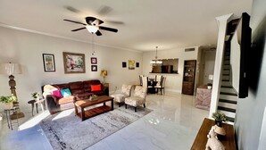 A spacious living room with a ceiling fan, a dining area, and a kitchen in the background. - Energy Corridor - long term rental. Utilities included!! (Houston)