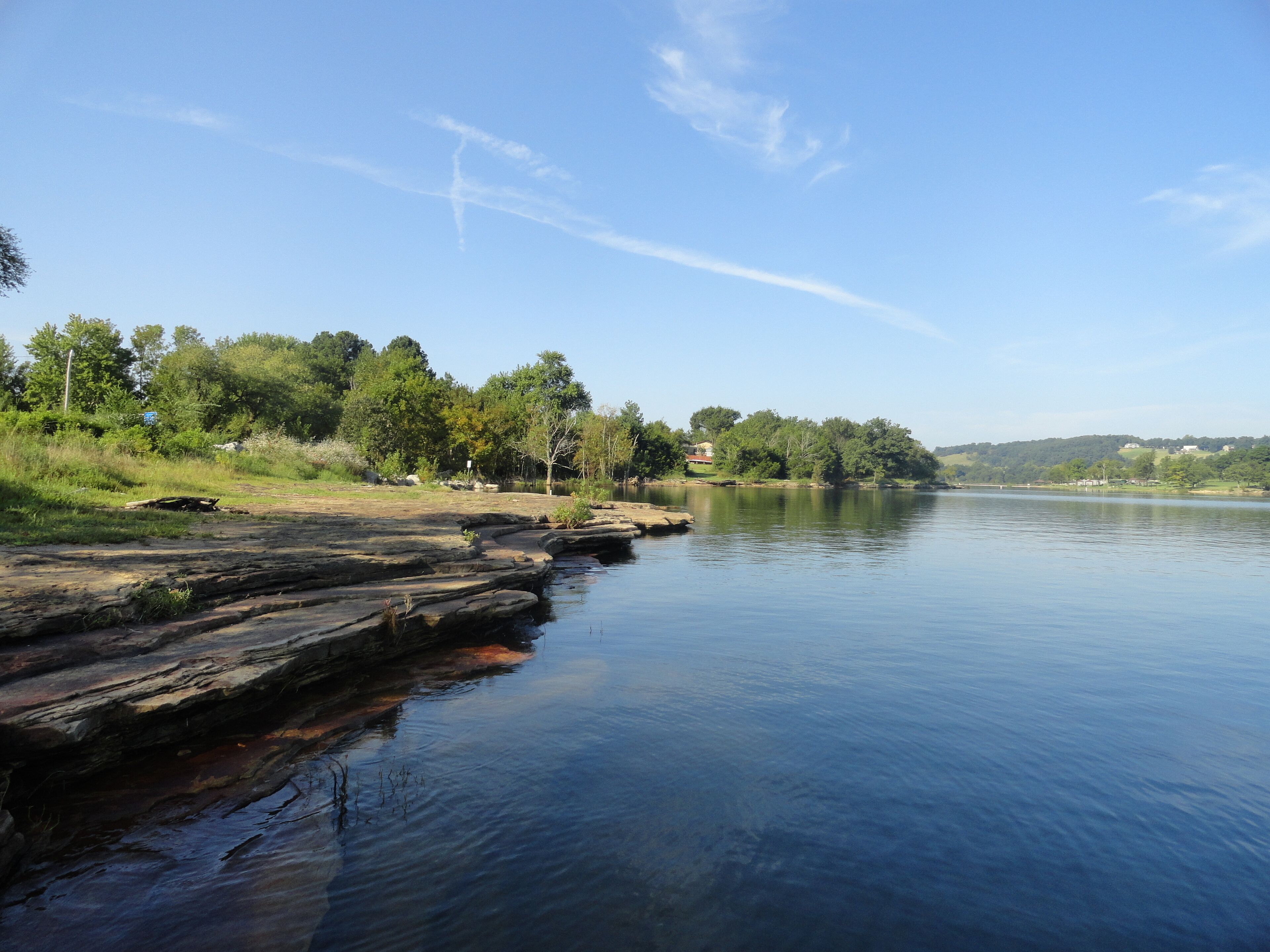 Ein ruhiger Fluss mit steinigen Ufern und Bäumen.