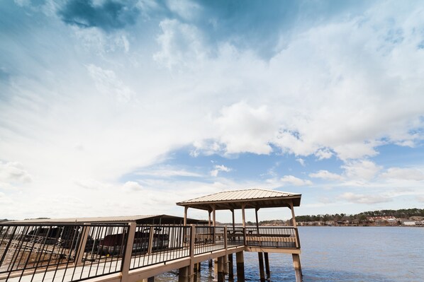 A wooden pier extending into a body of water with a covered seating area and a metal railing.