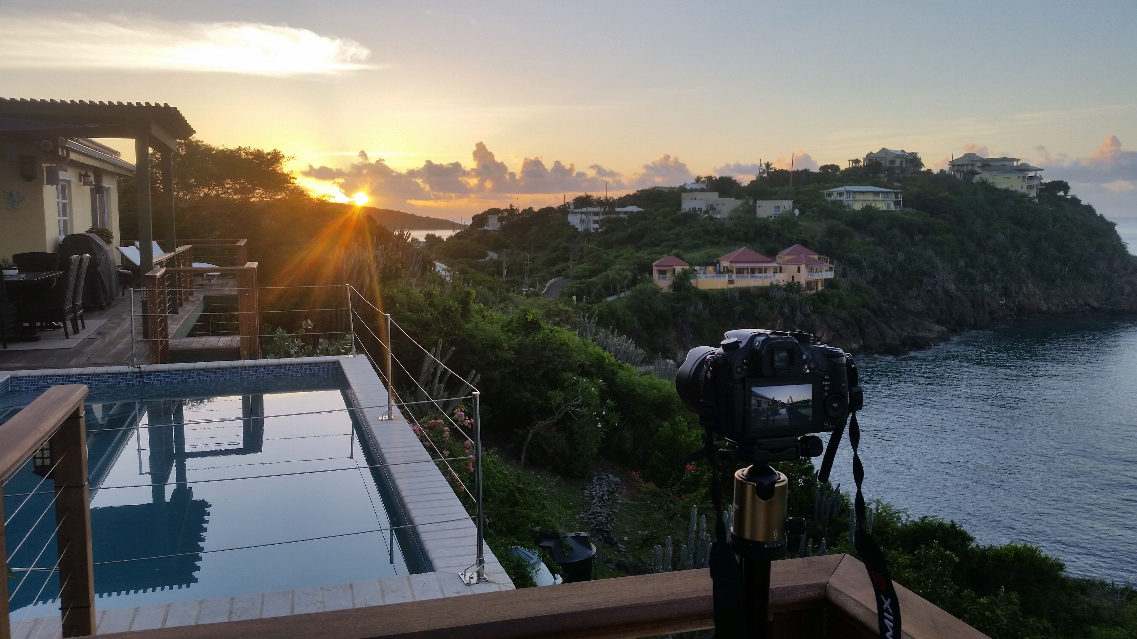 Una cámara sobre un trípode mirando una piscina con el atardecer al fondo.