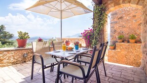 Eine Terrasse im Freien mit Tisch, Stühlen und Sonnenschirm.