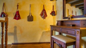 Eine hölzerne Bank, eine Holzkommode und ein Spiegel in einem Raum mit Holzboden und einer gelben Wand.