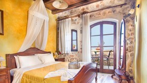 Ein Zimmer mit einem großen Bett, einem Holz-Kopfteil, einem Nachttisch mit Lampe sowie einem weiteren Nachttisch und einem Fenster mit Vorhängen.