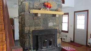 A cozy room with a stone fireplace, a wooden bed, and a red ottoman. - Classic mountain cabin with beautiful stone fireplace in a rural setting (Plumtree)