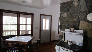 A kitchen with a stone wall, wooden table, chairs, and a white stove. - Classic mountain cabin with beautiful stone fireplace in a rural setting (Plumtree)