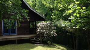 A wooden cabin with a blue door and a covered porch. - Classic mountain cabin with beautiful stone fireplace in a rural setting (Plumtree)