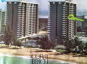 A high-rise hotel with multiple balconies overlooking a beach.