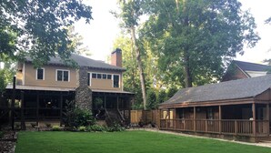 A two-story house with a stone chimney, a covered porch, and a well-maintained lawn.