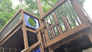 A wooden playground structure with a blue slide and a circular viewing platform.