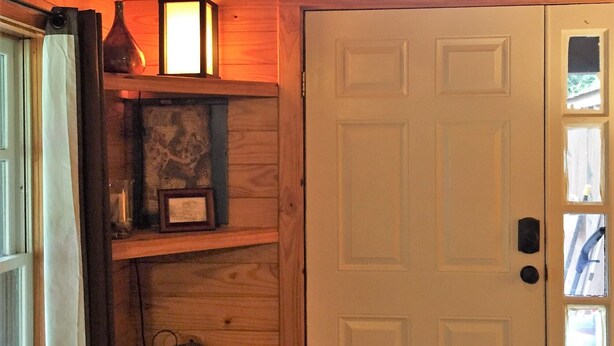A wooden interior with a white door, a small window, and shelves with various items.