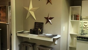 A compact kitchen with a central island, stools, and a stove.