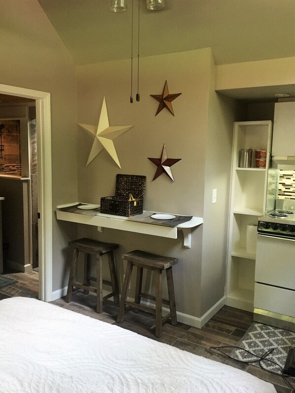 A compact kitchen with a central island, stools, and a stove.